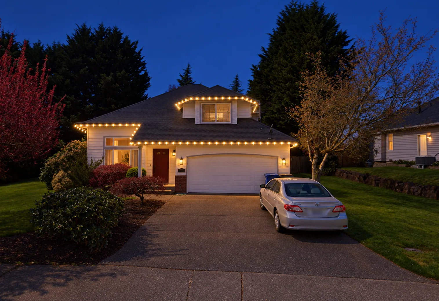 Warm white Christmas lights outlining a two-story home's roofline at dusk